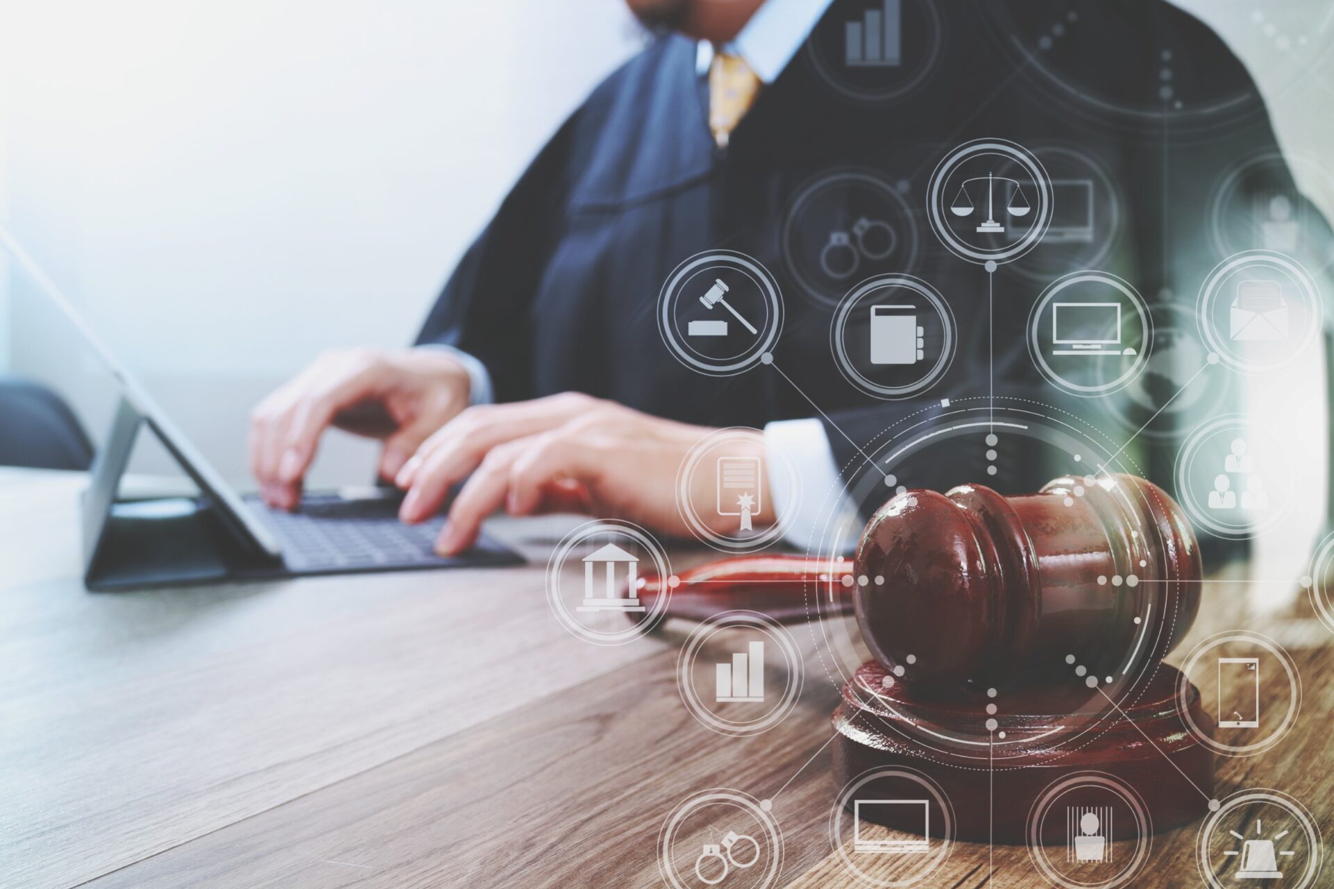 Male judge in a courtroom with the gavel,working with digital tablet computer docking keyboard on wood table